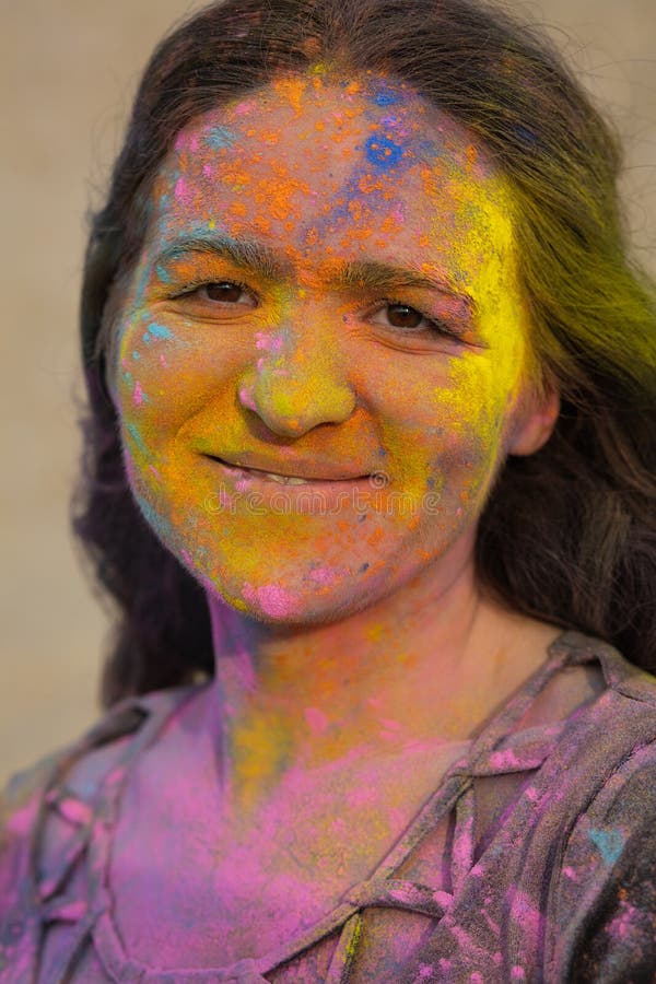 Lovely brunette model with wavy hair covered with colorful dry paint Holi at the desert. Lovely brunette woman with wavy hair covered with colorful dry paint royalty free stock photos